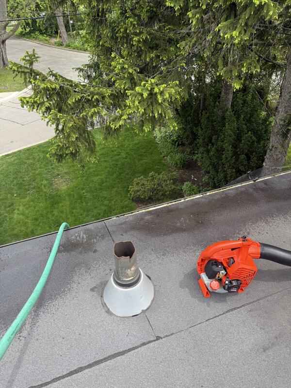 Leaf blower and hose used to clean a flat roof and its gutters